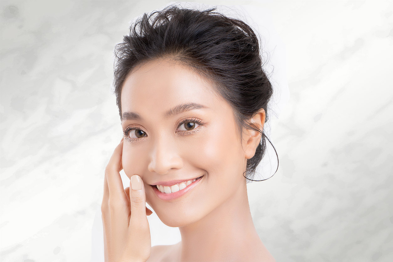 Image of Asian woman with hand on face | Facial Treatments | GGFM Aesthetics
